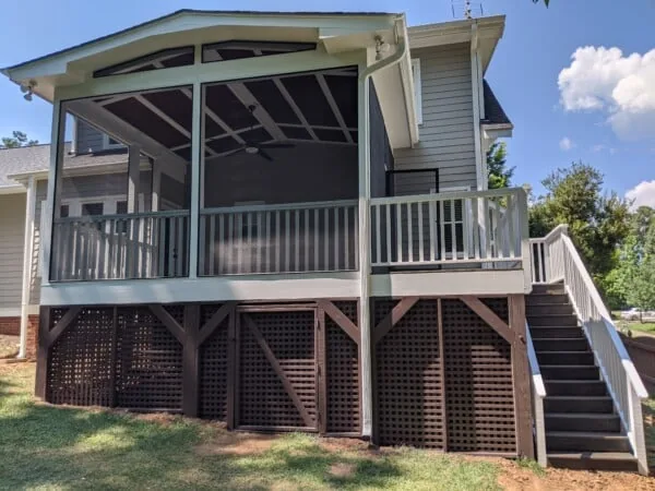 Raised screened porch with white railings and stairs to the yard
