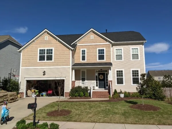 Two-story tan home with a new roof and gutters