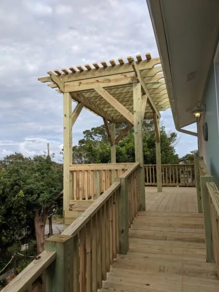 Wood deck with a pergola and stairs down a wooded slope