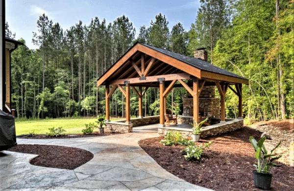 Timber-frame pavilion over a stamped concrete patio in a wooded backyard
