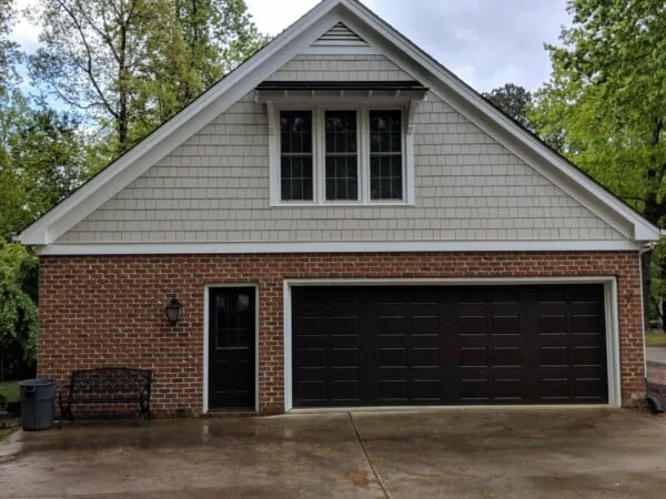 Two-car garage with freshly painted shake siding above brick