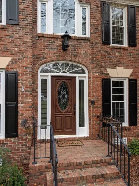 Brick home entry with a new wood front door and arched window