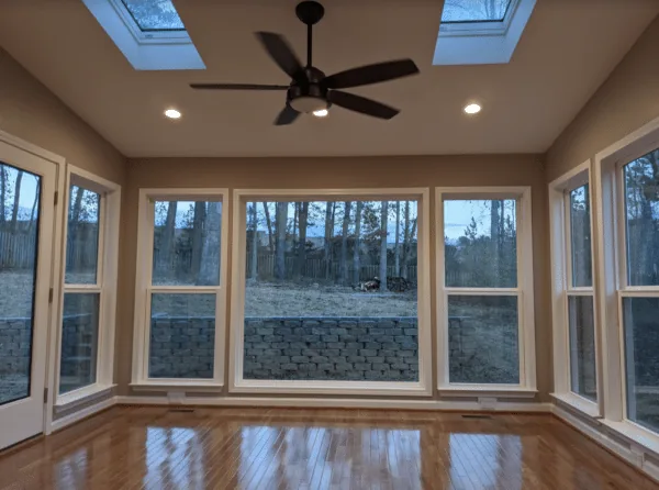 Sunroom interior with skylights, ceiling fan, and walls of windows